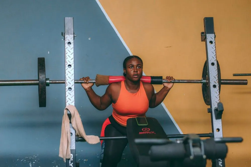A woman sets up to squat a loaded barbell in a power rack.